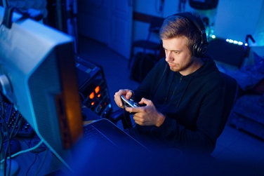 male-gamer-in-headphones-holds-joystick-and-playing-videogame-on-console-or-desktop-pc-gaming-lifestyle-cybersport-computer-games-player-in-his-room-with-neon-light-streamer_266732-1077.jpg